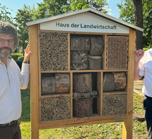 Zwei Männer neben einem Insektenhotel.