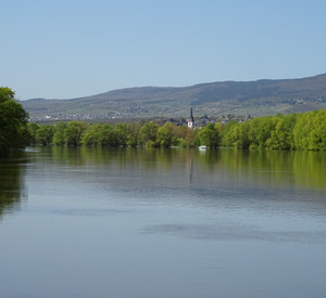 Gewässer Flussverlauf mit Uferbewuchs sowie Aussicht auf ein Dorf
