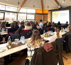 Viele Menschen in einem Saal, die einer Referentin zuhören.