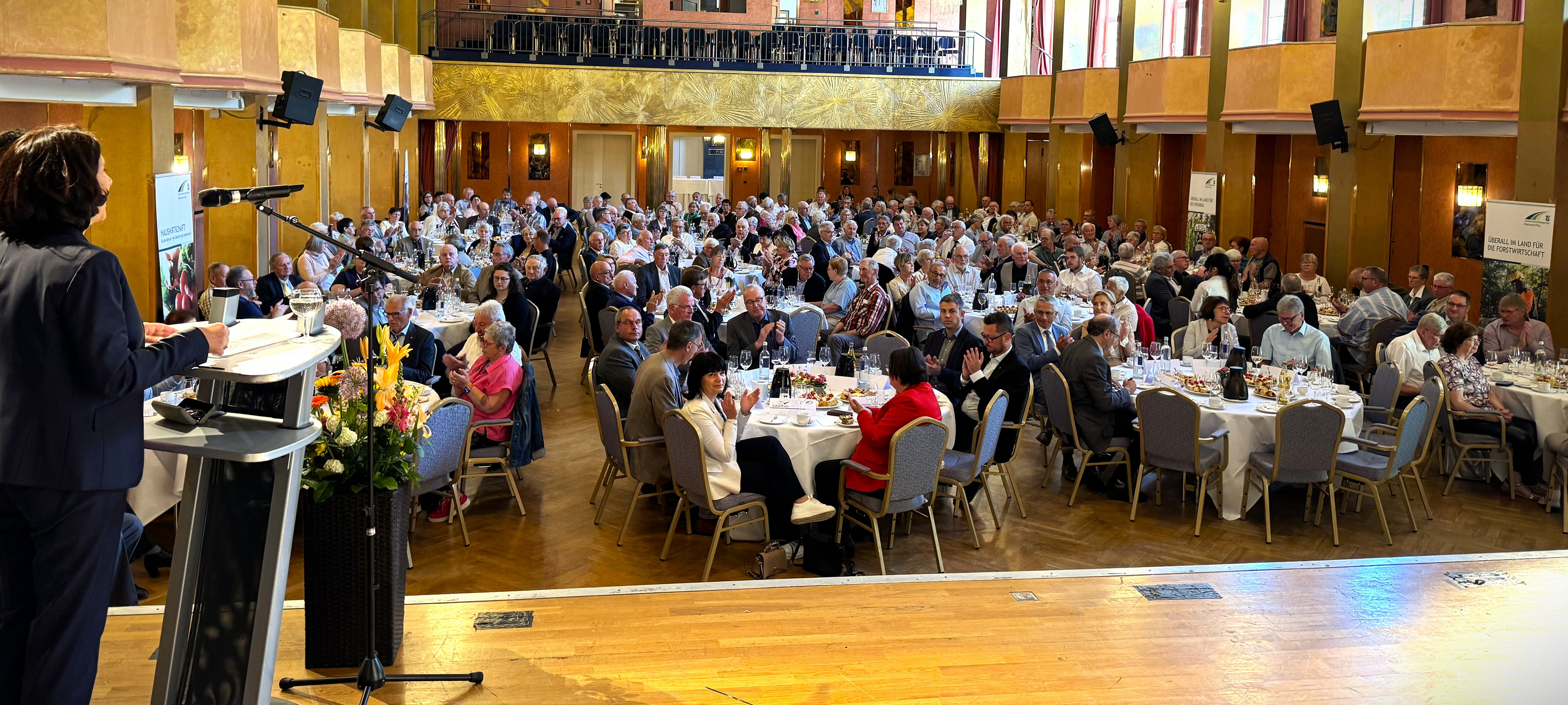 Viele Menschen im Saal an runden Tischen