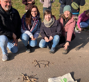 Menschen basteln mit Zweigen Dinge auf dem Boden.