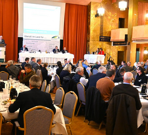 Delegierte an Tischen, vorne ein Podium.