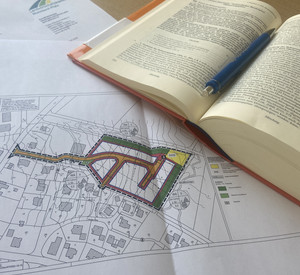 Aufgeschlagenes Baugesetzbuch und eine Planzeichnung eines Bebauungsplanes liegen auf einem Schreibtisch