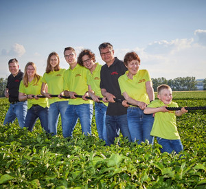 Familie zieht an Seil in einem Feld.